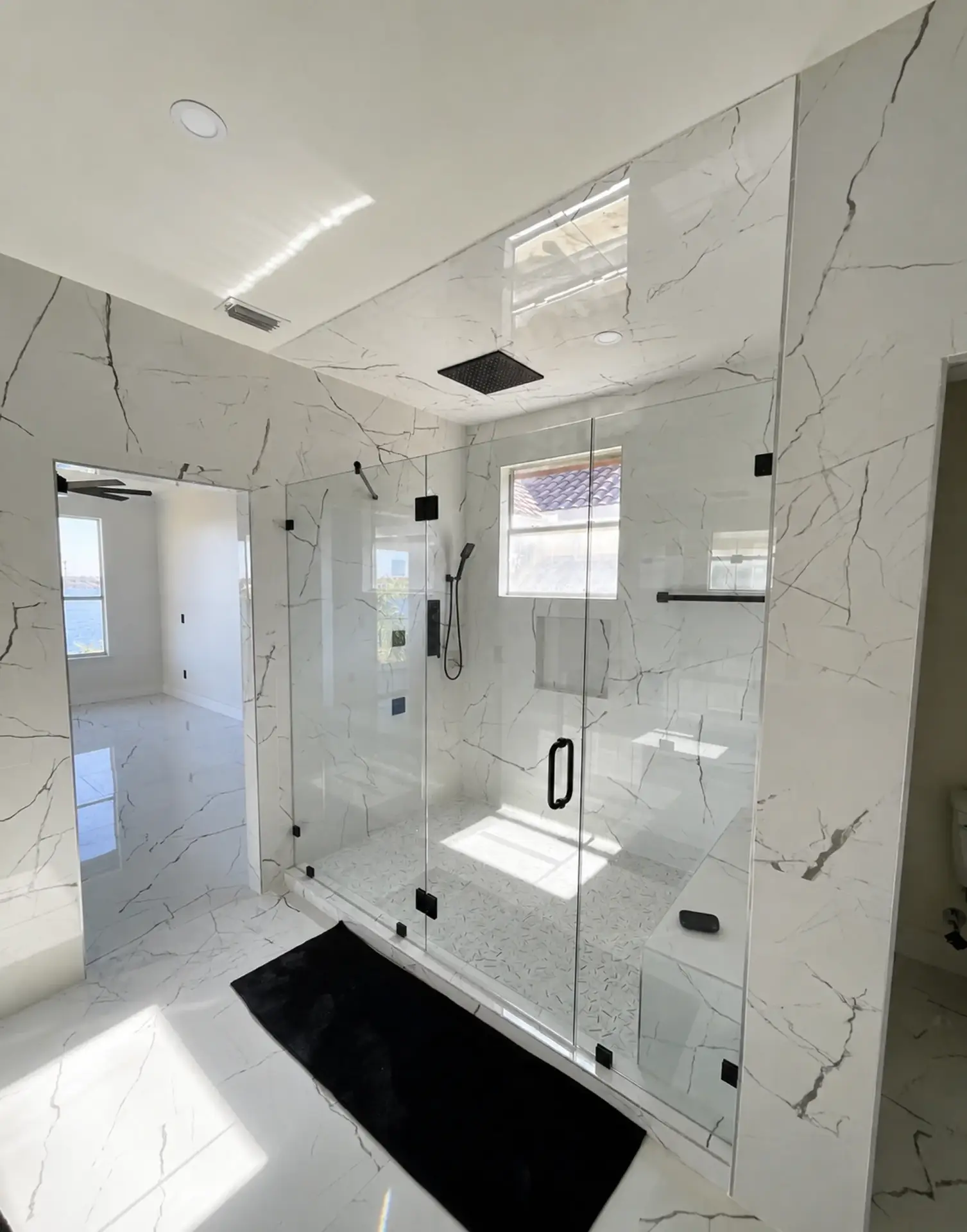 Completed BML Construction shower remodel with marble-look wall panels, grab bars, and built-in seating